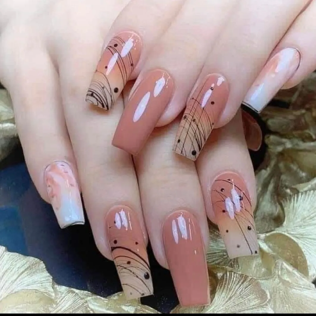 Nude-peach coffin nails with fine black line art over gold leaves