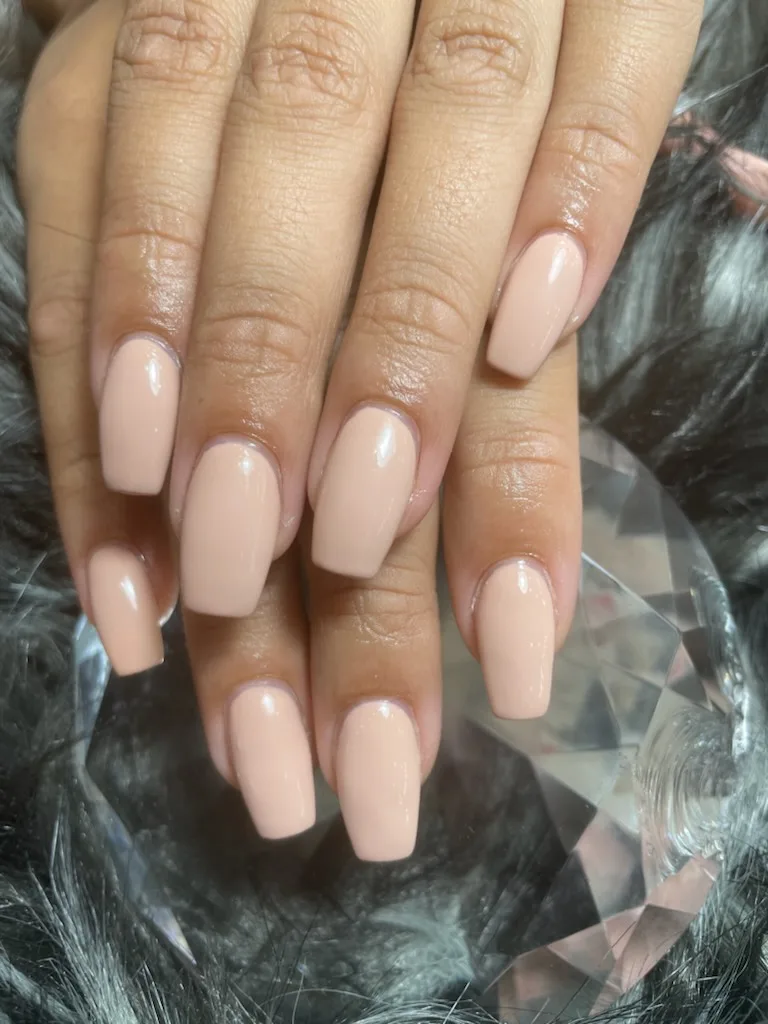 Clean nude-peach coffin nails on crystal and grey fur