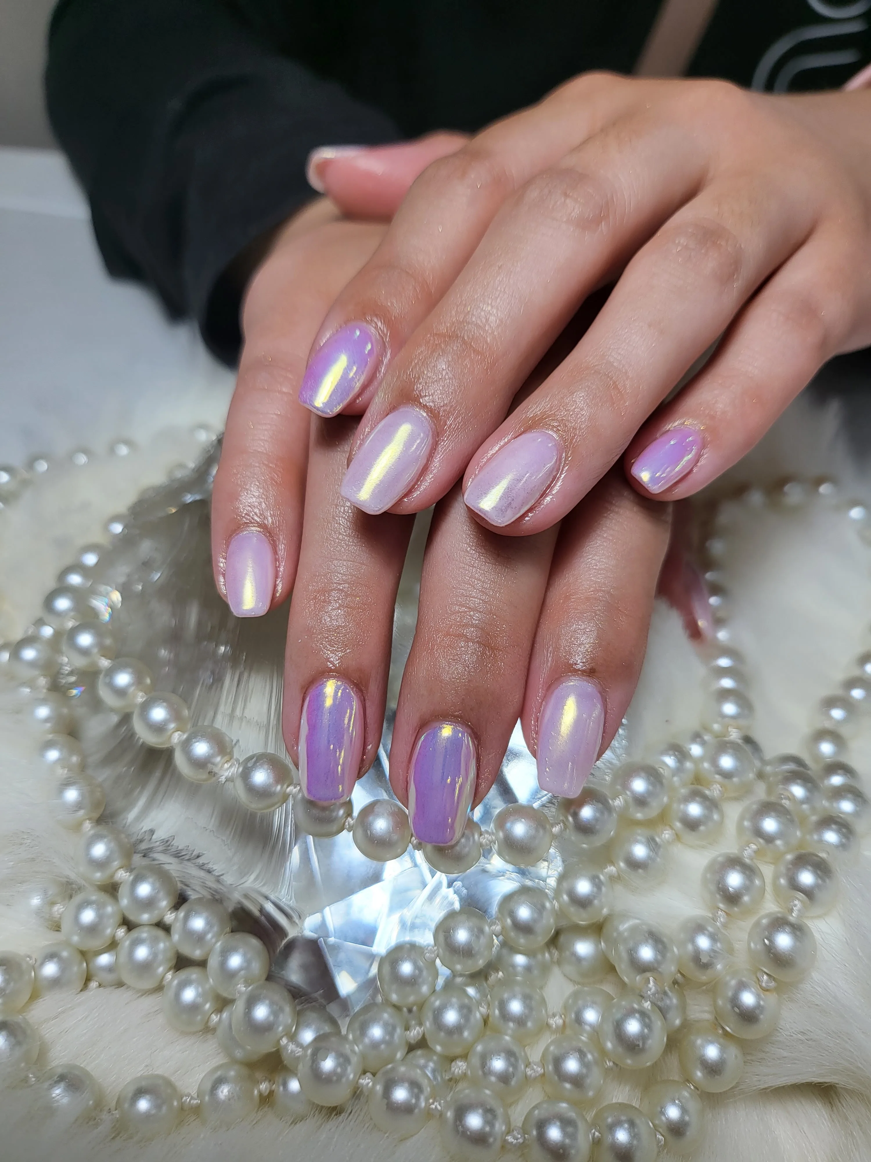 Pearlescent chrome-white nails resting on pearls and crystal