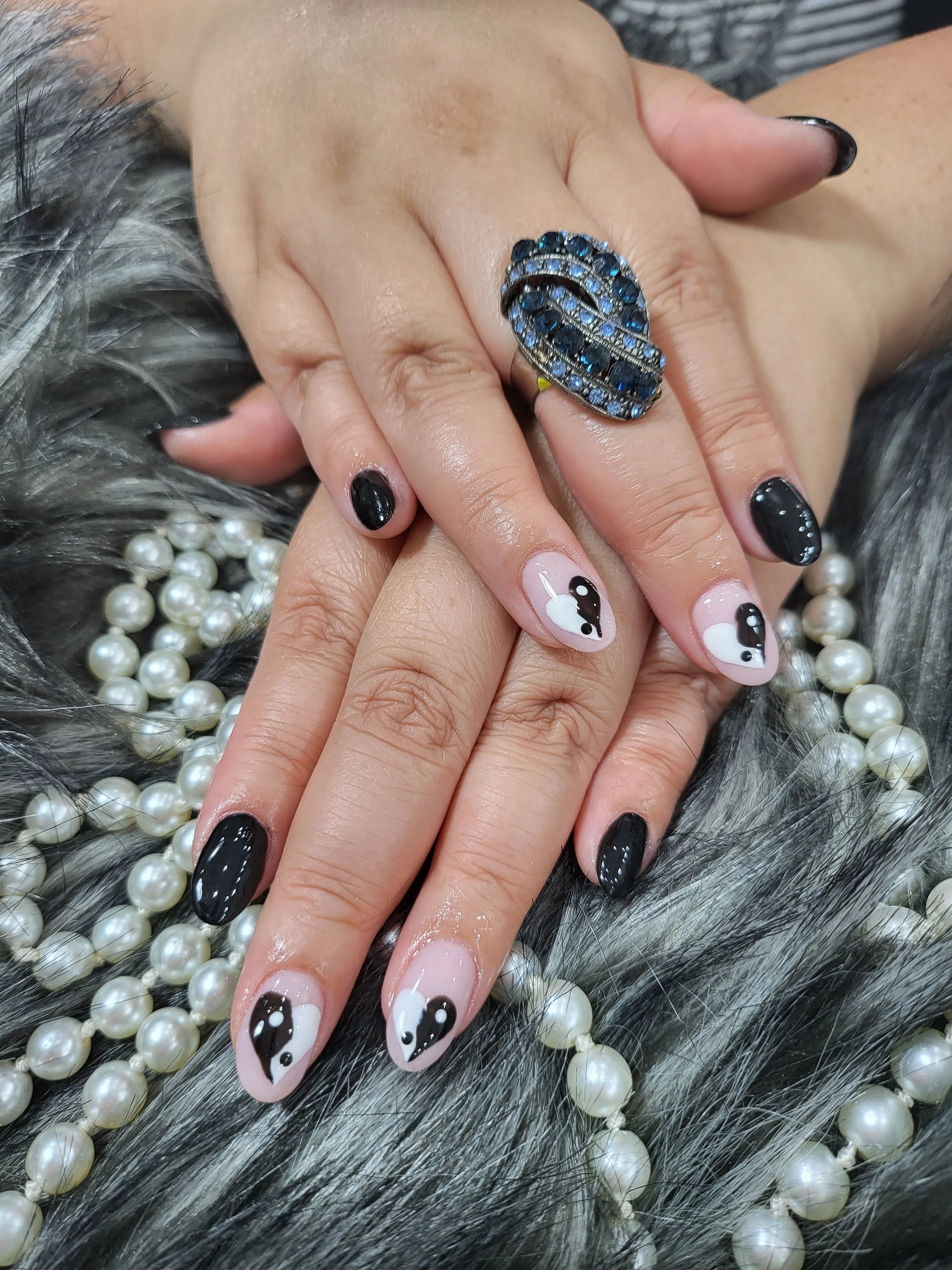 Black and white heart-design nails on fur with pearls and blue ring