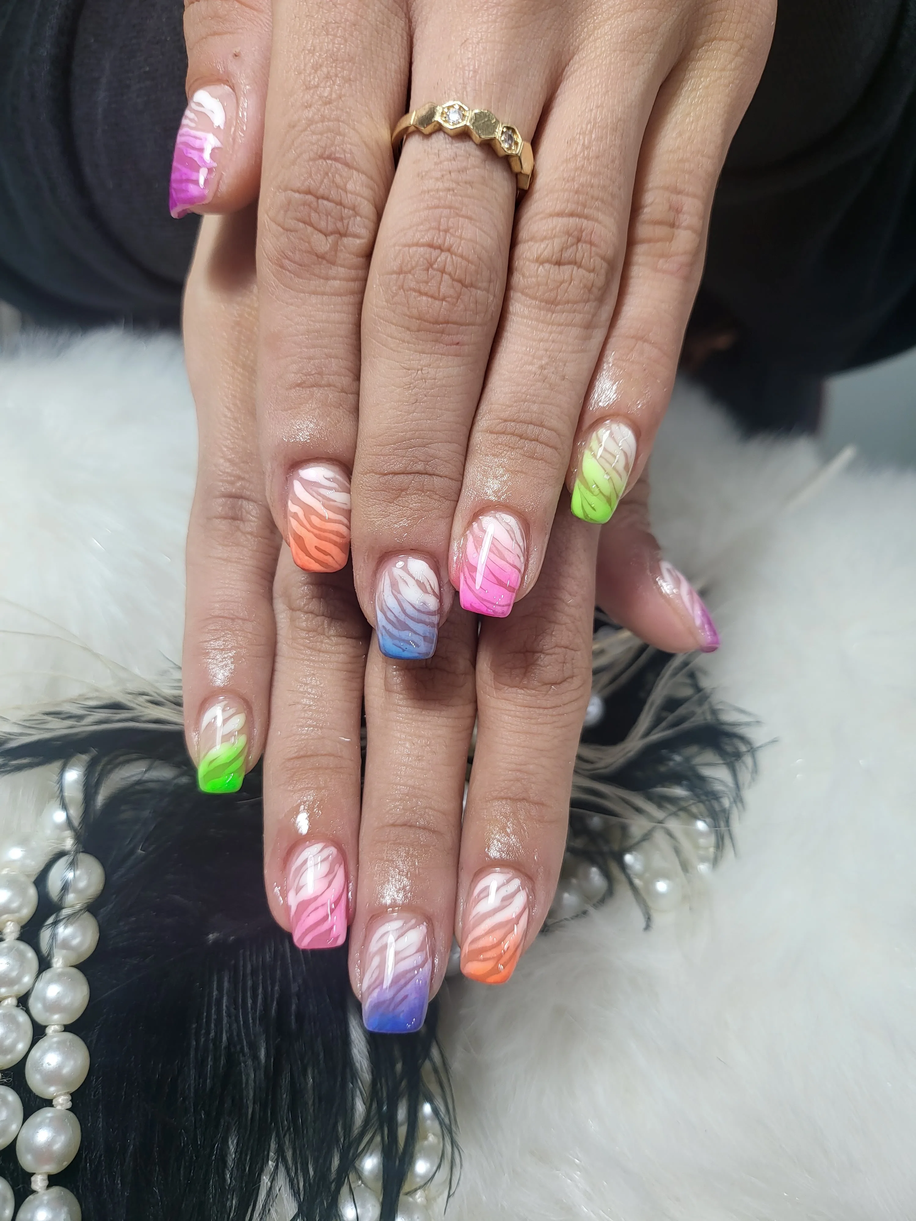 Rainbow zebra-stripe ombre nails with gold ring and feathers